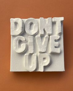 the words don't give up are made out of white foam on an orange background