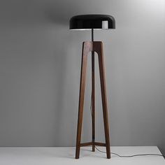 a wooden floor lamp with a black shade on the base and a white light behind it