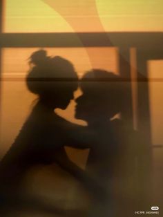 the silhouette of two people in front of a window