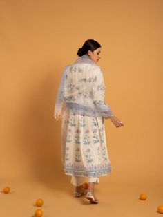 Set of 3 consists of kurta, pants, and dupatta. Reviving the age-old technique of hand block printed florals in lavender and blue set on a majestic bed of ivory soft handwoven cotton. Kurta: Delicately gathered kurta with ghera adorned in hand block printed flowers, 3/4th sleeves, and silver gota detailing on the hemline & sleeves, set in pure cotton Dupatta: Handwoven kota doria dupatta, complete with customized block prints Pants: Ivory straight-fit pants in soft cotton. Fit: Fitted at bus Traditional Cotton Sharara With Floral Print, Traditional Cotton Kurta With Sheer Dupatta, Cotton Salwar Kameez With Sheer Dupatta, Traditional Cotton Lawn Suit With Sheer Dupatta, Cotton Lawn Suit With Sheer Dupatta, Floral Print Mulmul Dupatta For Navratri, Bollywood Style Floral Print Mulmul Dupatta, Floral Print Mulmul Dupatta, Bohemian Salwar Kameez With Sheer Dupatta In Mulmul