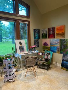 an artist's studio with large windows and paintings on the wall