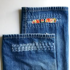 two pairs of jeans with embroidered designs on them