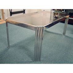 a glass table with metal legs on carpeted floor