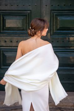 a woman in a white dress is walking down the street with her back to the camera