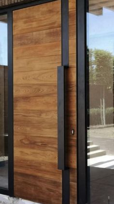 a modern wooden door with black frame and glass doors on the outside of a building