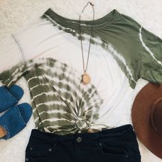 a tie - dyed shirt, jeans and hat are laid out on a white carpet