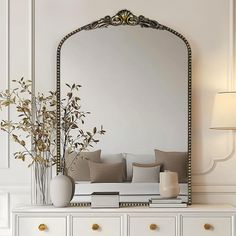 a white dresser topped with a mirror and vase filled with flowers