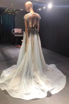 the back of a wedding dress on display in a room with lights and drapes