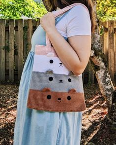 a woman carrying a crocheted bag with cats on it