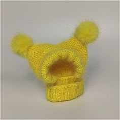 a yellow knitted hat with two pom - poms