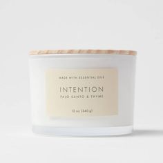 a white candle with an orange label on it and the words intention in front of it