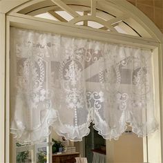 an open window with white curtains and lace