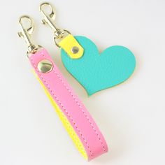 two heart shaped key fobs are shown on a white surface with a yellow and pink strap