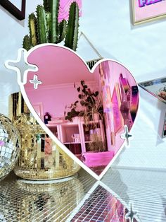 a heart shaped mirror sitting on top of a table next to a potted plant