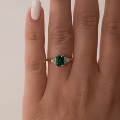 a woman's hand with a ring on it and an emerald stone in the middle