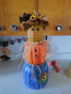 a scarecrow sitting on top of a pumpkin in the middle of a kitchen counter