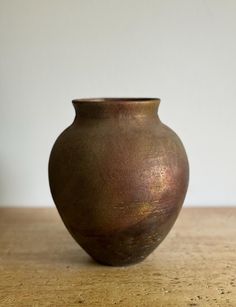 a brown vase sitting on top of a wooden table