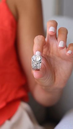 a woman is holding her hand up to the camera with a diamond ring on it