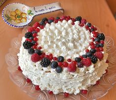 a cake with berries, raspberries and blueberries on it sitting on a table