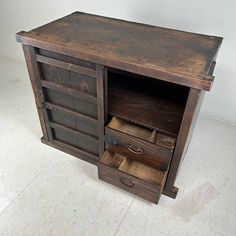 an old wooden cabinet with two drawers and one open drawer on the bottom, sitting in a white room