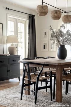 a dining room table with chairs and a vase on the table in front of it