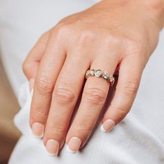 a woman's hand wearing a gold ring with three stones on the middle finger