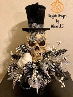 a fake skull wearing a top hat and scarf with white flowers in it's centerpiece