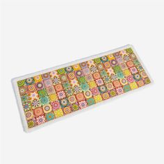 a place mat with colorful squares and flowers on it, sitting on a white surface