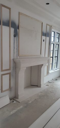 an empty room with white walls and fireplace in the middle, surrounded by construction materials