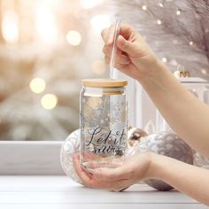 a person holding a glass jar with the words let it snow on it