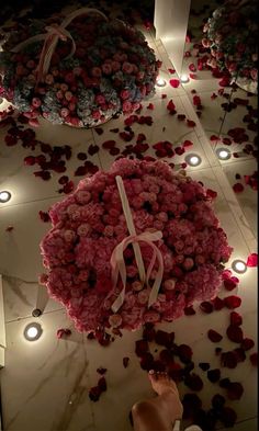 a large bouquet of flowers on the ground with candles around it and some lights in the background