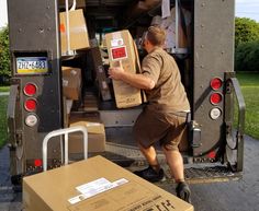 a man unloading boxes from the back of a moving truck with his hand on the door