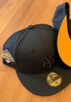 two new era hats are laying on the floor next to each other, one is black and yellow