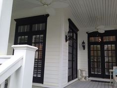 the front porch of a house with black doors and shutters