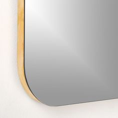 a mirror mounted to the side of a white wall next to a wooden framed object