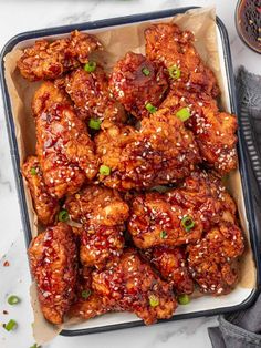 chicken wings with sesame seeds and green onions in a pan