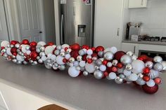 a kitchen counter topped with lots of christmas ornaments and balloons in the shape of letters