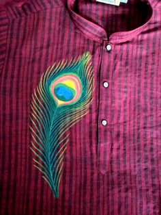 a red shirt with a green and blue peacock feather on the left side of it