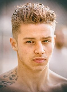 a close up of a person with tattoos on his chest and shoulder, looking at the camera