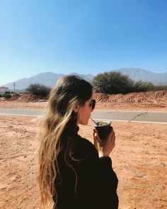 a woman eating food in the desert with mountains in the background