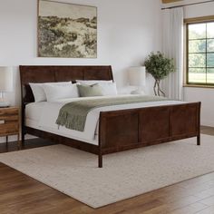 a large bed sitting in a bedroom on top of a hard wood floor next to a window