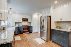 Kitchen remodel with white upper cabinets, a grey backsplash, light granite countertops, new vinyl plank flooring, and farm sink under the bay window