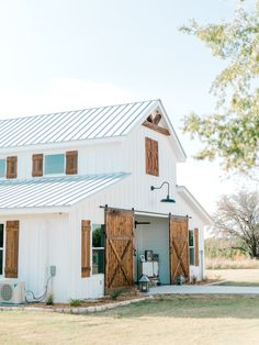 a white barn with wooden doors and windows