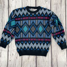 "1990s Vintage Gabrielle brand pullover sweater has major Coogi vibes. Geometric diamond and zig-zag pattern with real black leather detailing across the front. This well-made crewneck has multiple knitted textures, ribbed cuffs and waist. Black with vibrant teal, blue, red, white, and a little bit of tan.  Very good vintage condition. Marked as a Size Medium.  (Vintage sizes may vary from today's modern sizing, so please refer to measurements to ensure correct fit.) Measurements are taken with 90s Style Black Winter Sweater, Winter Crew Neck Sweater With Geometric Pattern, Retro Crew Neck Sweater With Argyle Pattern, Winter Geometric Pattern Crew Neck Sweater, Retro Crew Neck Argyle Sweater, Retro Argyle Pattern Crew Neck Sweater, Retro Long Sleeve Argyle Sweater, Fitted Vintage Multicolor Sweater, 1990’s Sweaters