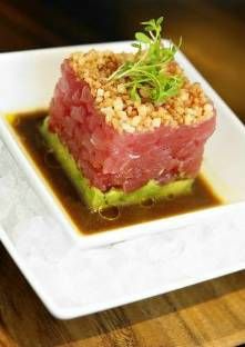 a white plate topped with meat covered in sauce and garnished with green leaves