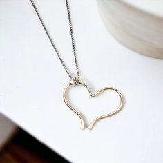 Indulge in the timeless elegance of our Open Heart Necklace. The delicate sterling silver chain is home to a handcrafted gold open heart charm, adorned with shimmering silver beads. Exquisitely combining luxury and sophistication, this necklace is a must-have for any wardrobe. Sterling Silver Chain Adjustable Lenth from 15" - 18" Handmade 14k Gold Filled Open Heart Charm Sent in a Ribboned Gift Box with Polishing Cloth Handmade in Montana Heart Charm Pendant Necklace For Everyday, Everyday Heart Charm Pendant Necklace, Valentine's Day Charm Necklace For Everyday, Dainty Everyday Charm Necklace With Heart Beads, Dainty Heart Beads Charm Necklace For Everyday, Everyday Heart Pendant Charm Necklace With Delicate Chain, Minimalist Everyday Heart Necklace With Adjustable Chain, Dainty Heart Necklace With Adjustable Chain For Everyday, Everyday Minimalist Heart Necklace