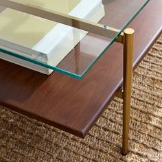 a coffee table with a glass top and wooden legs on carpeted area next to couch