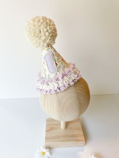 a wooden head with a white hat on it's top and flowers around it