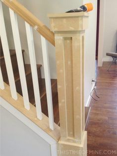 a bird sitting on top of a wooden post next to a banister in a living room