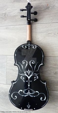 a black and white violin sitting on top of a wooden floor next to a wall